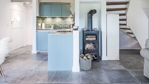 A modern kitchen with blue cabinets, a central island, and a wood-burning stove. - Stunning private villa for 4 people with WIFI, TV and panoramic view (Simonsberg)