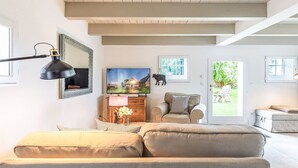 A living room with a sofa, a television, a lamp, and a framed picture on the wall. - Stunning private villa for 4 people with WIFI, TV and panoramic view (Simonsberg)