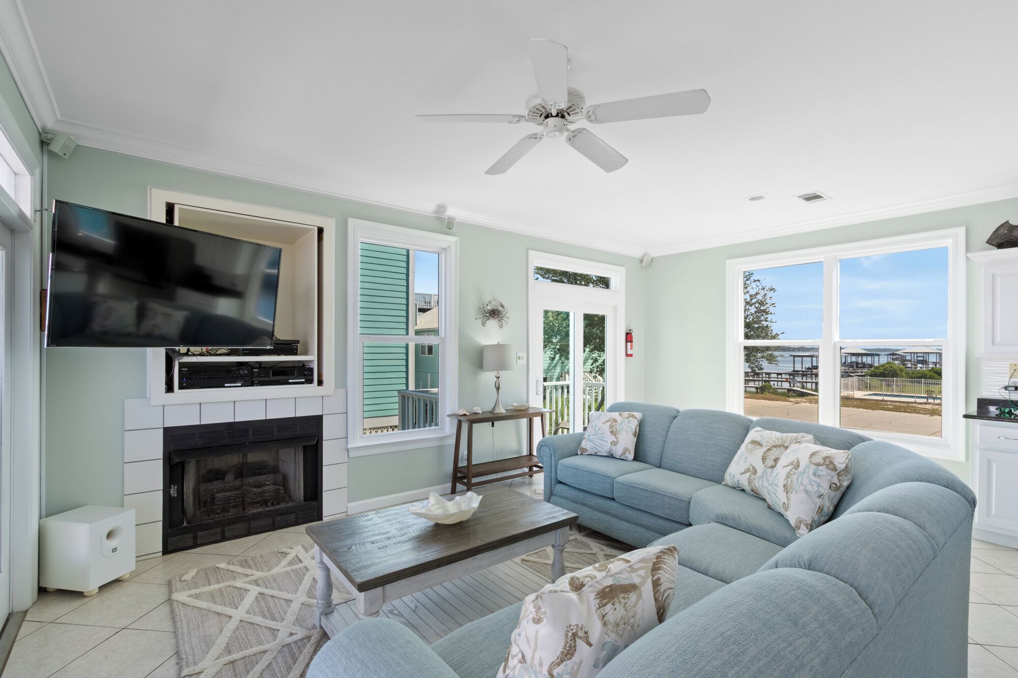 A living room with a television, fireplace, sofa, and a view of the outdoors.