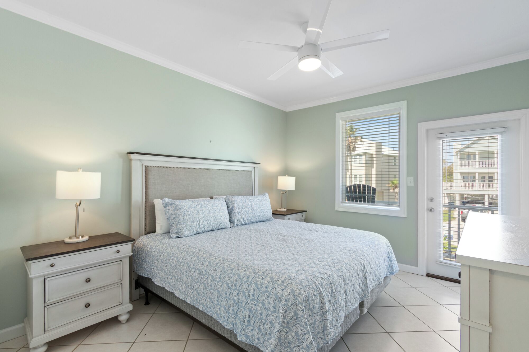 A bedroom with a bed, nightstands, a ceiling fan, and a window with blinds.