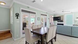 A dining area with a wooden table and chairs, a kitchen with a TV, and a blue couch.