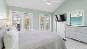 A bedroom with a bed, a dresser, a television, and a ceiling fan.