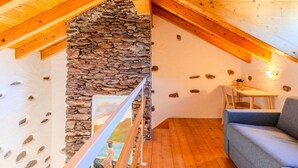 A cozy attic room with wooden beams, a stone wall, and a painting. - Wonderful private villa for 6 guests with WIFI, TV and patio (Calozzo)
