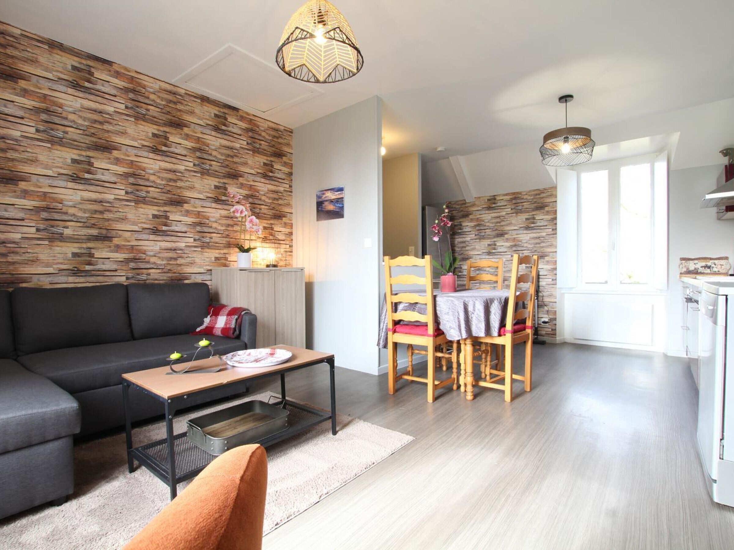 Een moderne woonkamer met een bank, eettafel, stoelen en een keukenhoek.