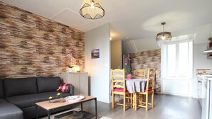 Un salon moderne comprenant un canapé, une table à manger, des chaises et un coin cuisine.
