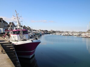 A marina with boats docked, a clear sky, and buildings in the background. - Charming House in Montfarville with Parking and Wifi, Pets Welcome (Montfarville)
