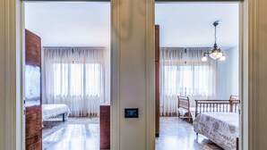 Une chambre d’hôtel avec un lit, une chaise, une table et un ventilateur de plafond.