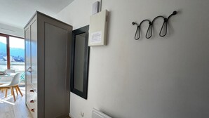Una cocina moderna con horno empotrado, microondas y un refrigerador pequeño. Se ve un comedor con mesa y sillas a través de una puerta abierta.