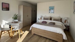Un dormitorio con cama, mesitas de noche, un escritorio, sillas, armario y lámpara en el techo.