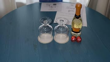A table with a bottle of Prosecco, two glasses, and two lollipops.