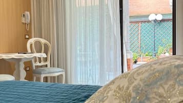 Un dormitorio con cama, escritorio, silla y vistas al exterior.