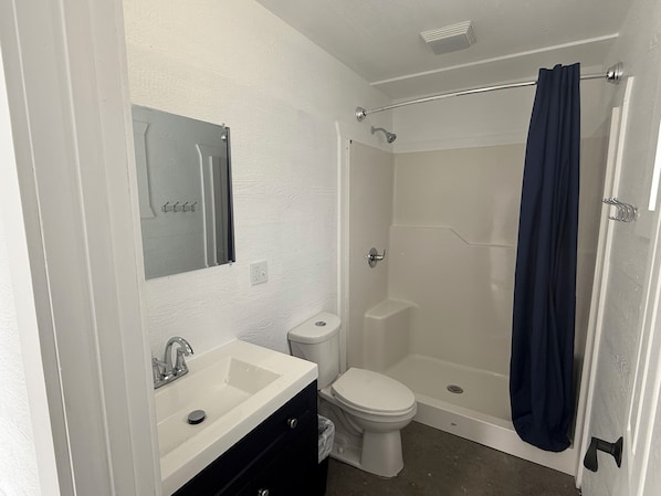Une salle de bain avec un lavabo blanc, des toilettes et une douche avec un rideau foncé.