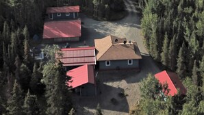 An aerial view of a residential area with multiple houses surrounded by dense forest. - Silver Cabin – Dry Cabin with Bunks | Fish On! (Sterling)