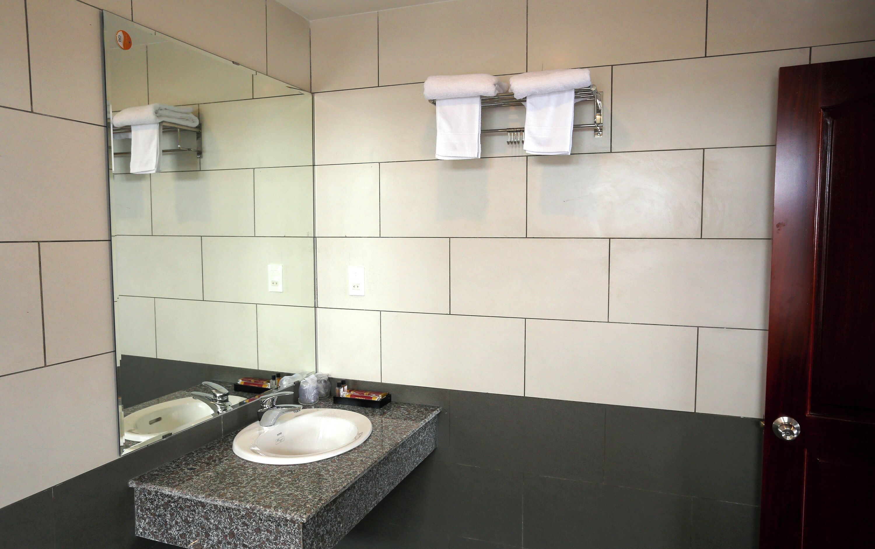 Un baño moderno con lavamanos de granito, un espejo y dos toalleros.