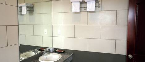 Un baño moderno con lavamanos de granito, un espejo y dos toalleros.