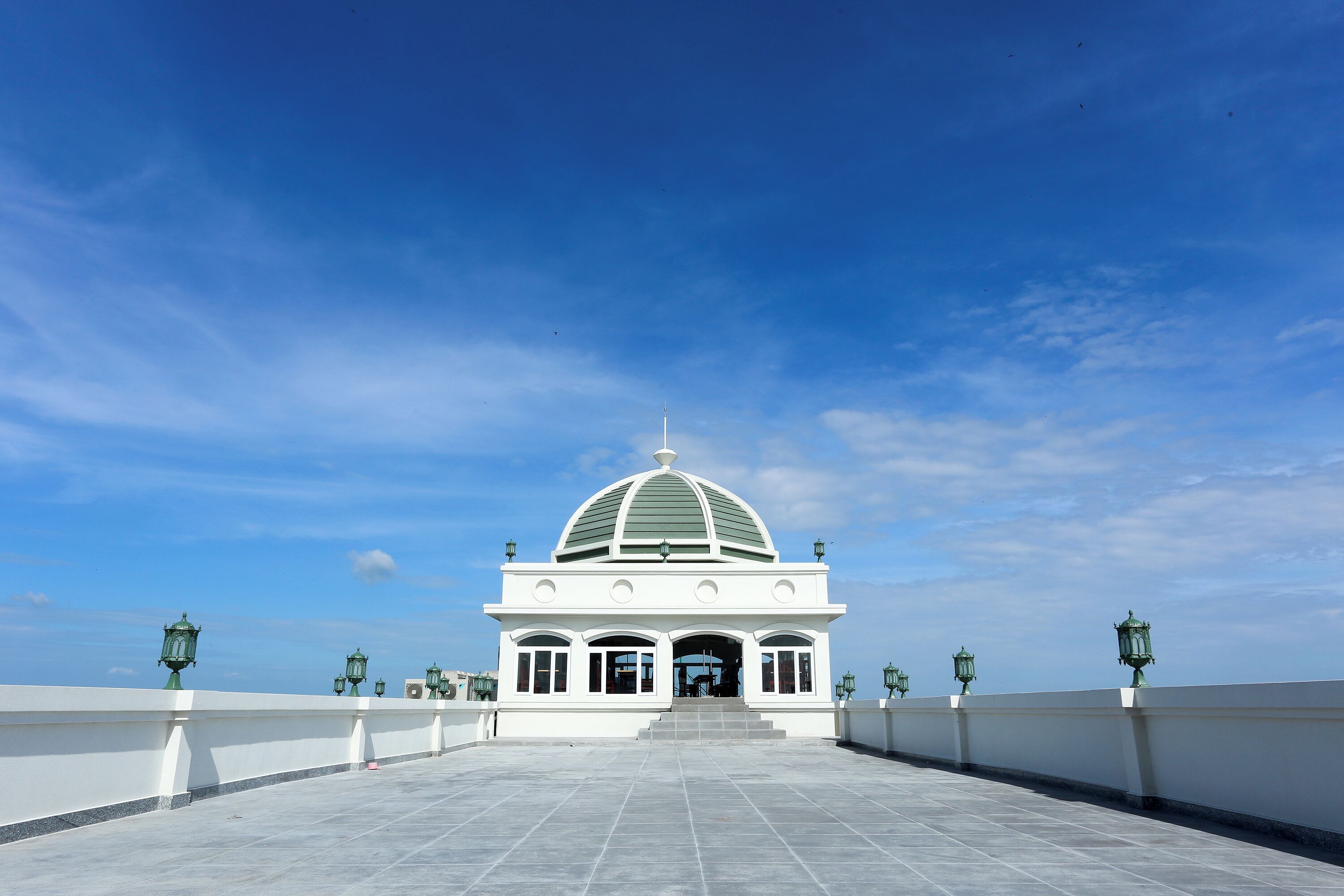 A white building with a dome roof and a tiled entrance area.