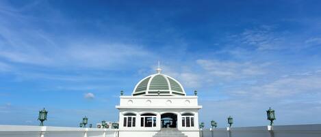 A white building with a dome roof and a tiled entrance area.
