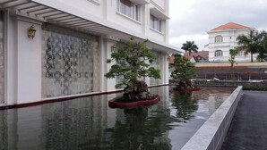 Ein Gebäude mit Wasserspiel und Bonsai-Bäumen.