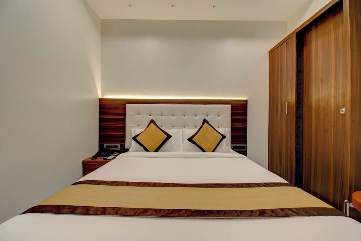 Ein Hotelzimmer mit einem großen Bett, einem Holzschrank und einem Nachttisch mit Telefon und Ladegerät.