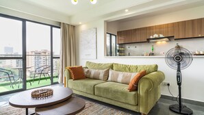 A modern living room with a green sofa, a round table, and a standing fan. - Skyline symmetry (Nairobi)