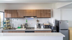 A modern kitchen with wooden cabinets, a stainless steel refrigerator, a built-in oven, and a coffee maker. - Skyline symmetry (Nairobi)