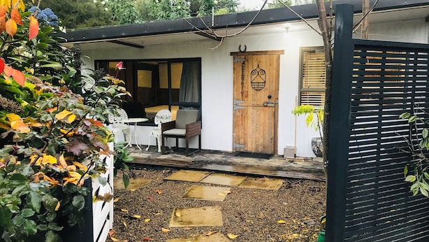 Ein Gartenbereich mit Sitzgelegenheit, einer Holztür und einem schwarzen Tor.