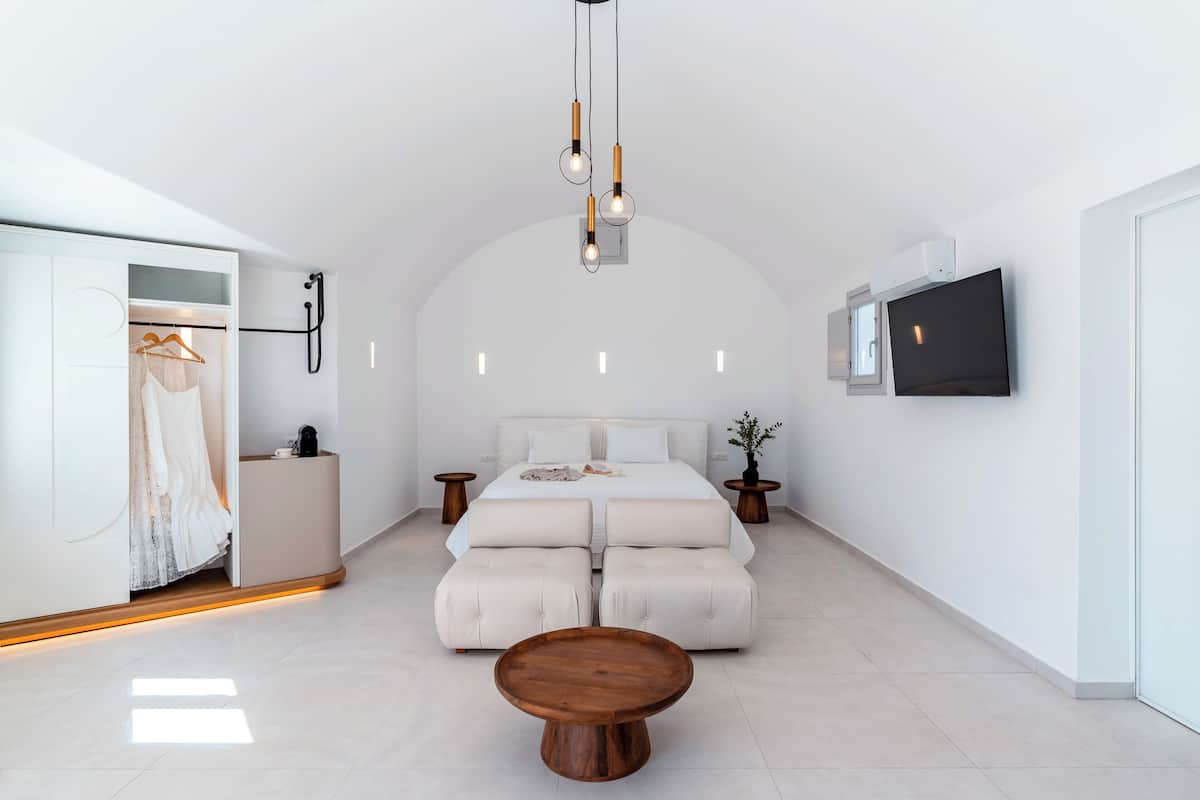 A modern bedroom with a large bed, a wooden coffee table, and a TV mounted on the wall.