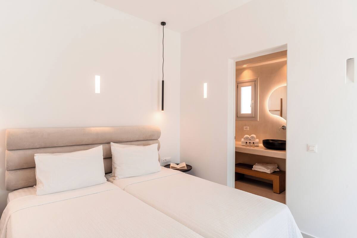 A modern bedroom with a large bed, bedside tables, and a built-in bench.