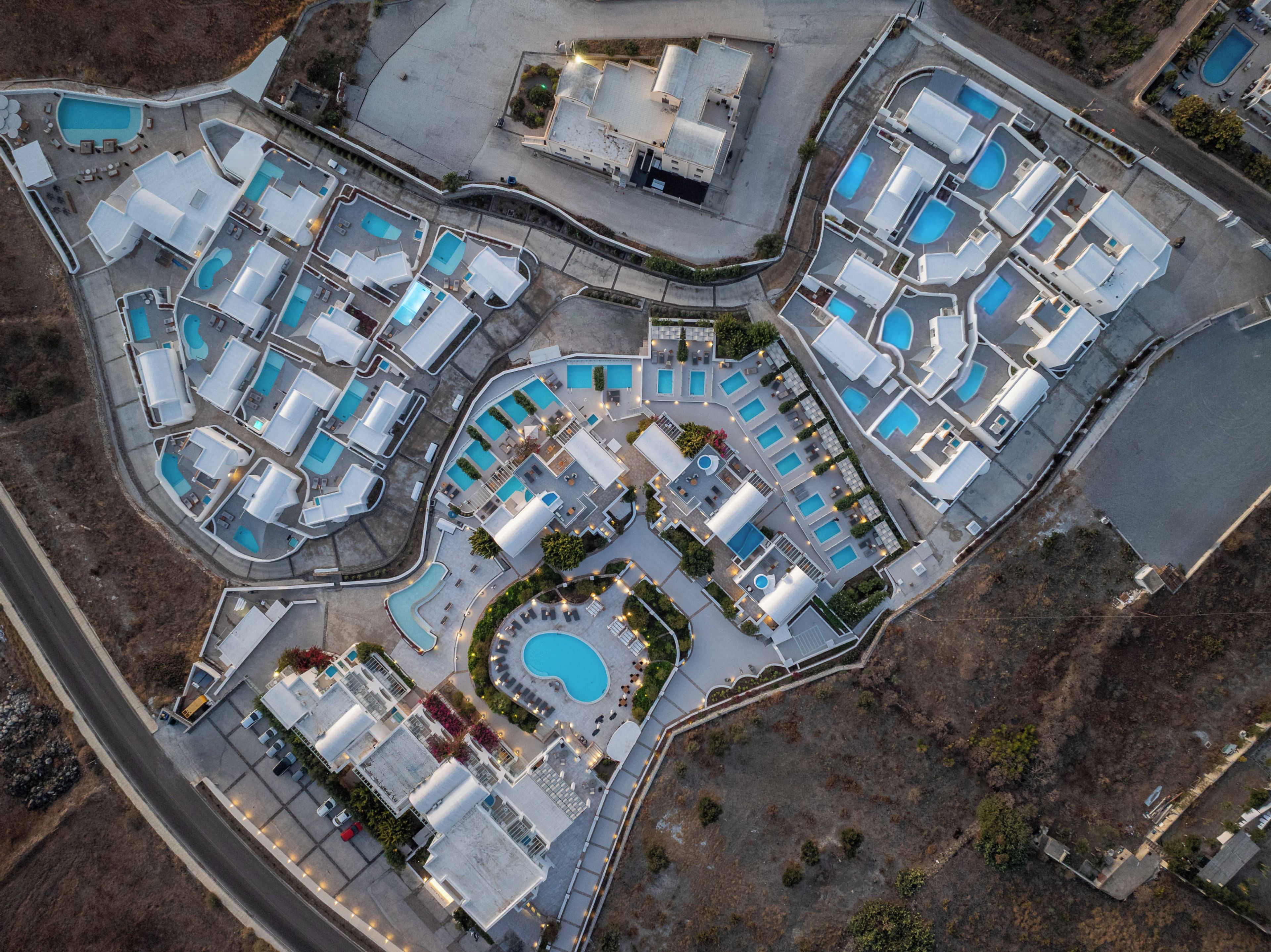 An aerial view of a resort with multiple swimming pools, guest rooms, and a central courtyard.