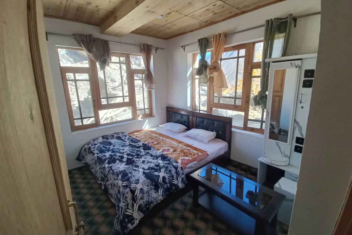 A bedroom with a bed, a dresser, and a window with curtains.