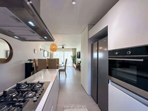 Una cocina moderna con una isla central, electrodomésticos de acero inoxidable y un comedor con sofá y mesa.