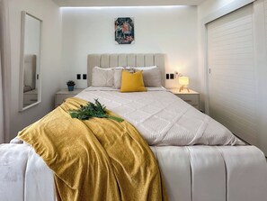 A neatly arranged bedroom with a bed, bedside tables, a mirror, and a wall-mounted artwork. - Beautiful new condo with Picuzzi (Punta Cana)