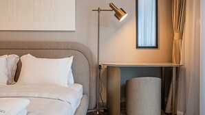 Une chambre d’hôtel moderne, équipée d’un lit, d’un lampadaire, d’une petite table et d’une fenêtre avec des rideaux.