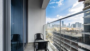 Un balcon doté d’une balustrade en verre, de deux chaises et d’une table.
