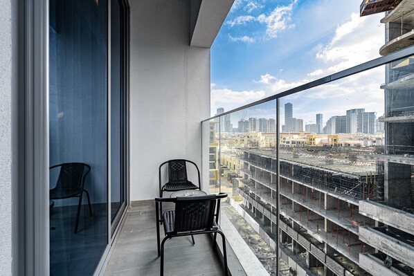 A balcony with a glass railing, two chairs, and a table. - Concept 7 211 in Dubai (Dubai)