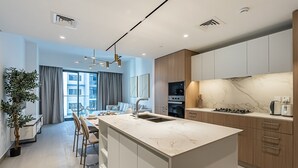 A modern kitchen with a marble countertop, wooden cabinets, and a central island. - Berkley Place 905 in Dubai (Dubai)
