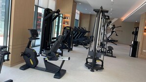 A modern gym with various exercise equipment, large windows, and a motivational wall. - Berkley Place 905 in Dubai (Dubai)