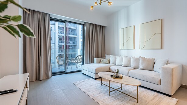 A modern living room with a sofa, coffee table, and a view of a building through large windows. - Berkley Place 905 in Dubai (Dubai)