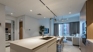 A modern kitchen with a central island, a dining area with a table and chairs, a sofa, and a large window with curtains. - Berkley Place 905 in Dubai (Dubai)