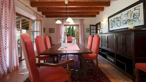 A dining area with a wooden table, red upholstered chairs, and a patterned rug. - Villa Reco de Marina (Sa Pobla)