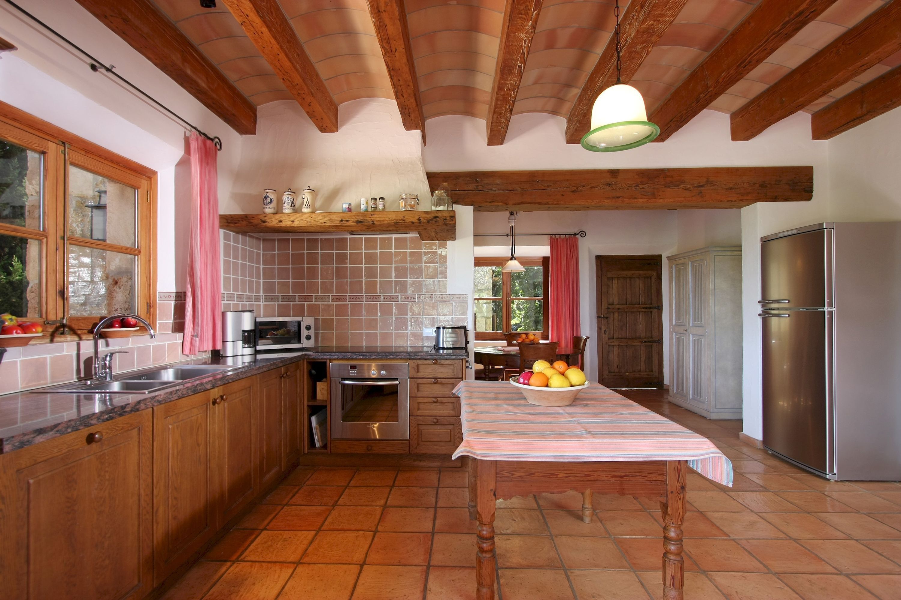 Cocina con armarios de madera, refrigerador de acero inoxidable y salpicadero de azulejos.