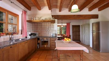 Cocina con armarios de madera, refrigerador de acero inoxidable y salpicadero de azulejos.