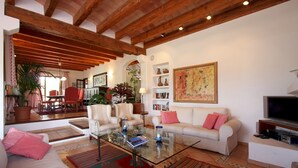 A spacious living room with a glass coffee table, a sofa, and a television. - Villa Reco de Marina (Sa Pobla)
