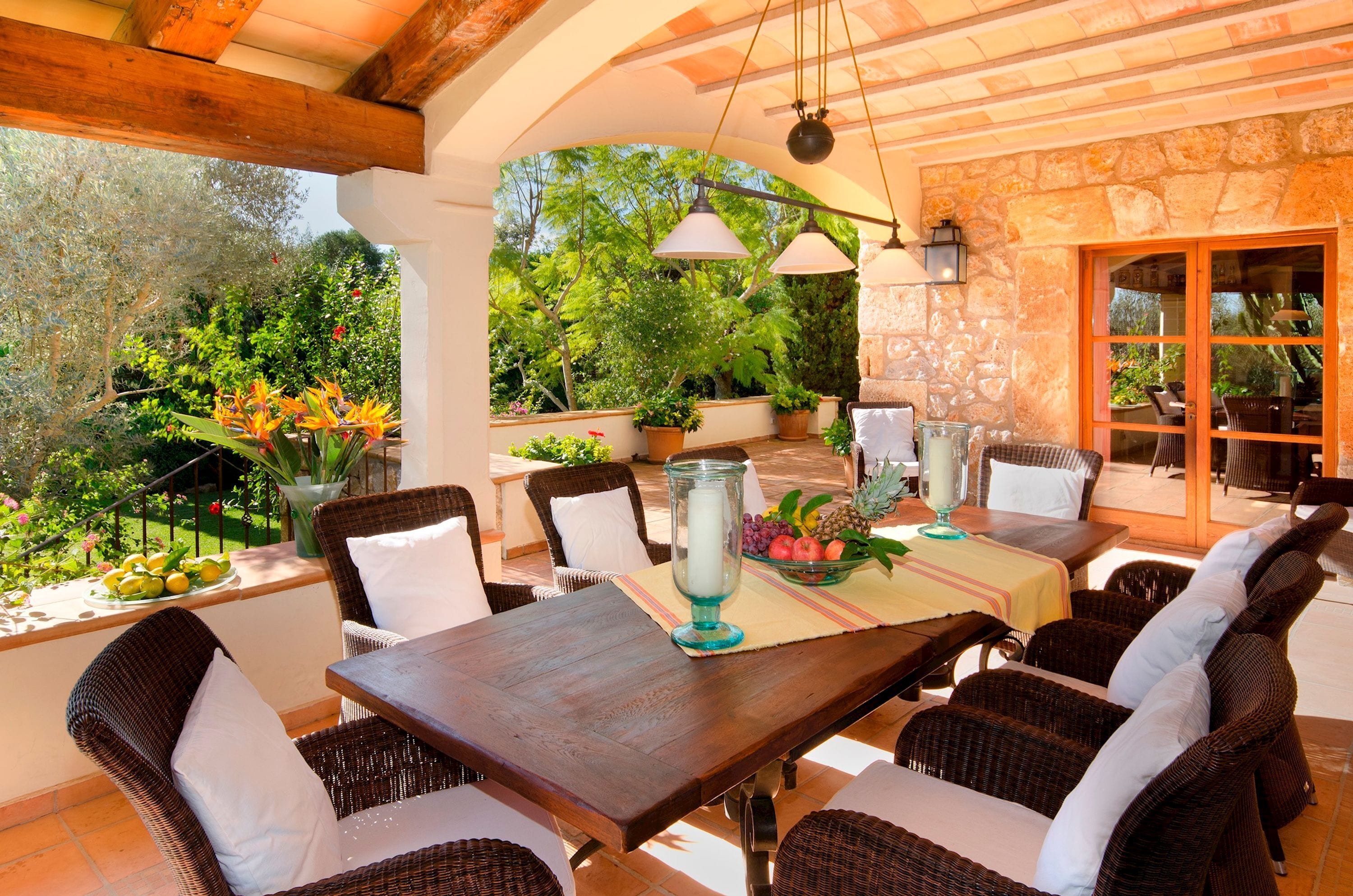 An outdoor patio with wicker furniture, a dining table, and a stone wall.