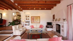 A spacious living room with a fireplace, a television, and a coffee table. - Villa Reco de Marina (Sa Pobla)