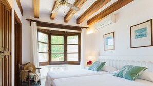 Une chambre avec deux lits, des poutres en bois, une fenêtre avec des rideaux et des tableaux encadrés au mur.