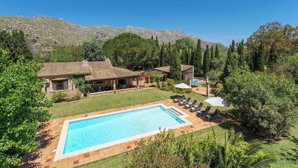 Un espace piscine offrant une vue dégagée sur le paysage environnant, notamment sur une maison et des montagnes en arrière-plan.