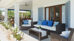A covered outdoor seating area with wicker furniture, a coffee table, and potted plants. - Villa Playa in Port de Pollen a (Pollenca)