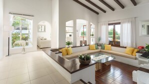 A spacious living room with a large sectional sofa, a glass coffee table, and a view of the outdoors. - Villa Playa in Port de Pollen a (Pollenca)