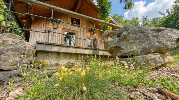 A wooden cabin with a balcony, surrounded by rocks and greenery. - Wooden Chalet Kalanka in Nature (Kanal)